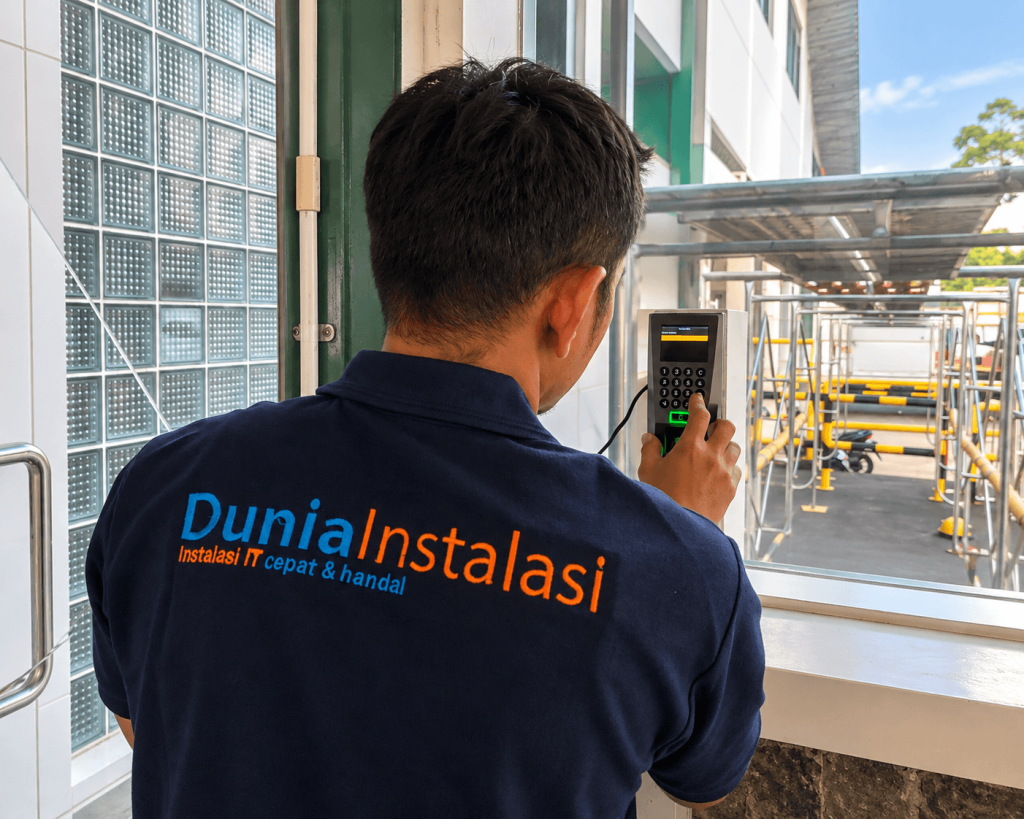 Teknisi Dunia Instalasi memasang mesin fingerprint untuk akses pintu